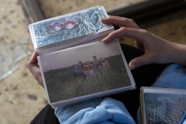 Marwa Al-Kayyali looks at photographs in her family photo album as she sits in the living room at her uncle’s apartment, which was damaged when a bomb was dropped in their neighborhood in Baalbek.